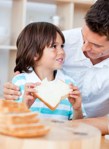 Menino adorável e seu pai comendo pão — Fotografia de Stock