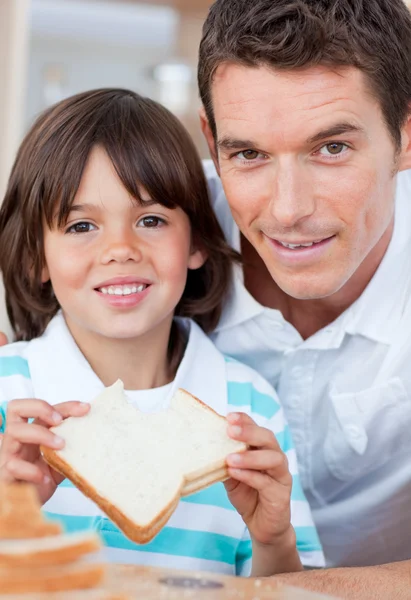 Portrait of a little boy and his father eating bread — Stock Photo, Image