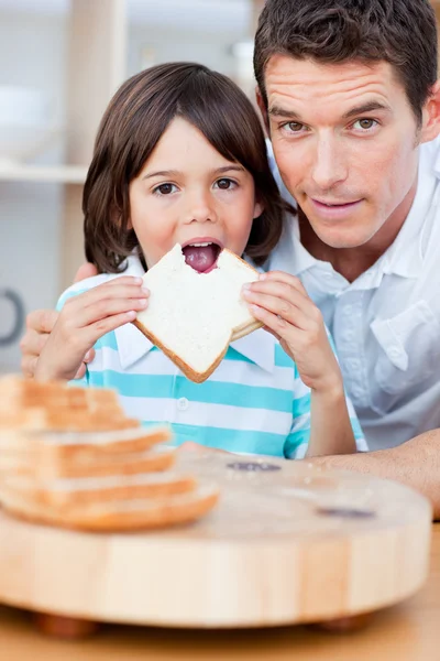 Cute little boy and his father eating bread — Stock Photo, Image
