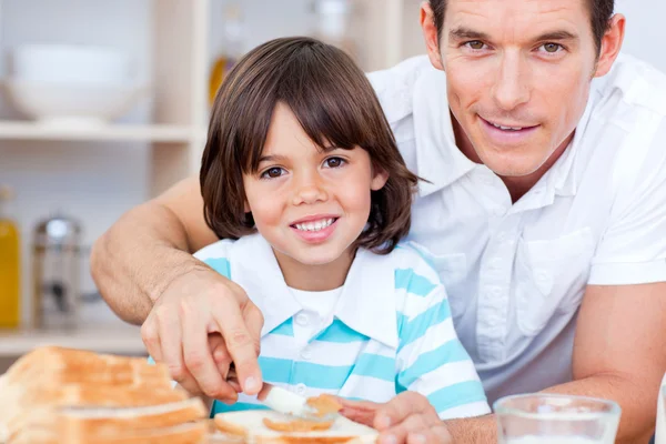 Portrait of a father and his son spreading jam on bread — Stock Photo, Image