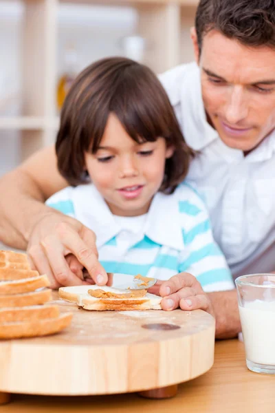 Padre cariñoso y su hijo extendiendo mermelada en el pan — Foto de Stock