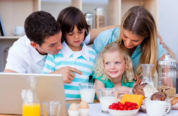 Veselé rodiny pomocí přenosného počítače během snídaně — Stock fotografie