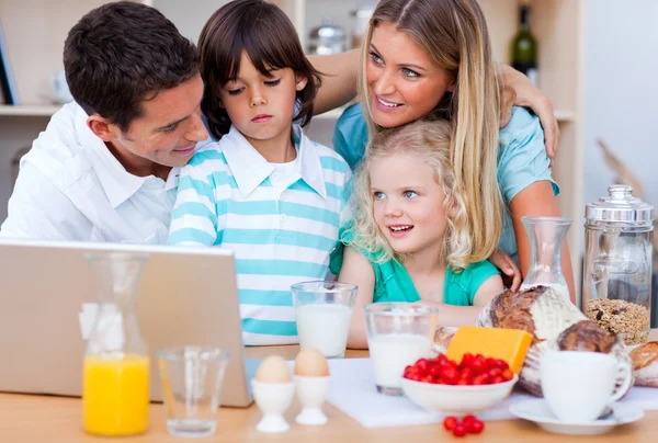 Счастливая семья с ноутбуком во время завтрака — стоковое фото