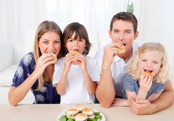 Éhes család eszik hamburgert a nappaliban — Stock Fotó