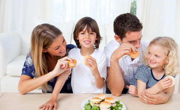 Adorável família comer hambúrgueres na sala de estar — Fotografia de Stock