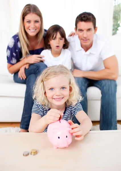 Blond liten flicka att infoga mynt i en piggybank — Stockfoto