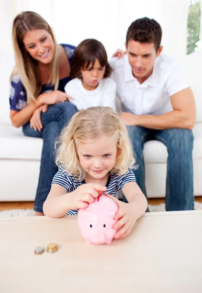 Bedårande liten flicka att infoga mynt i en piggybank — Stockfoto