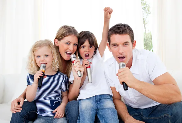 Retrato de una familia animada cantando a través del micrófono — Foto de Stock