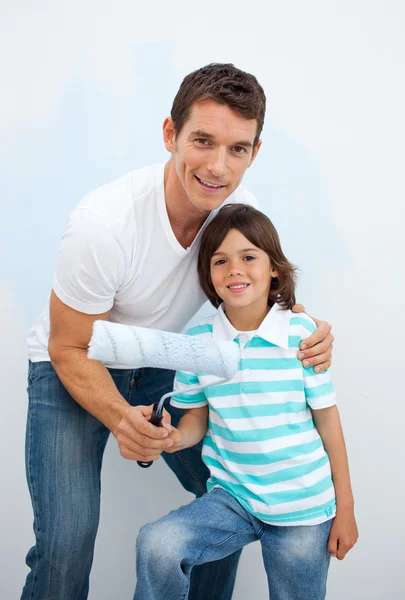 Uśmiechnięty ojciec i jego chłopiec paiting pokój — Zdjęcie stockowe