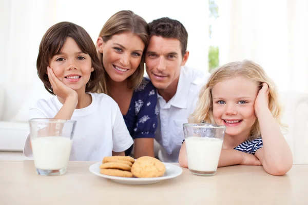 Kinderen koekjes eten en drinken melk met hun ouders — Stockfoto