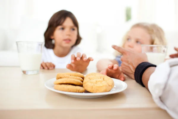 Siblings eatings biscuits and drinking milk — Stock Photo, Image