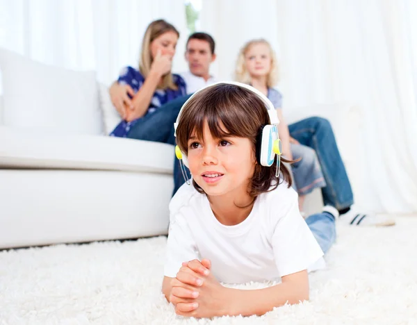 Glimlachend kleine jongen luisteren muziek liggend op de vloer — Stockfoto