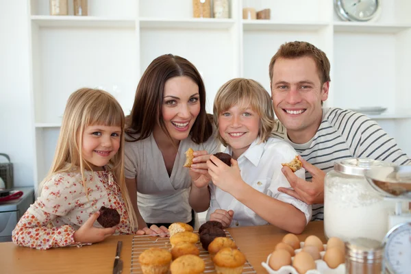 Crianças bonitas comendo muffins com seus pais — Fotografia de Stock
