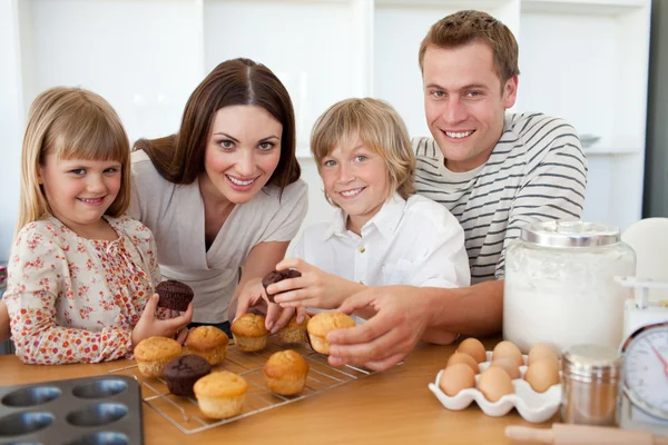 Smiling family eating their muffins in the kitchen — Stock Photo, Image