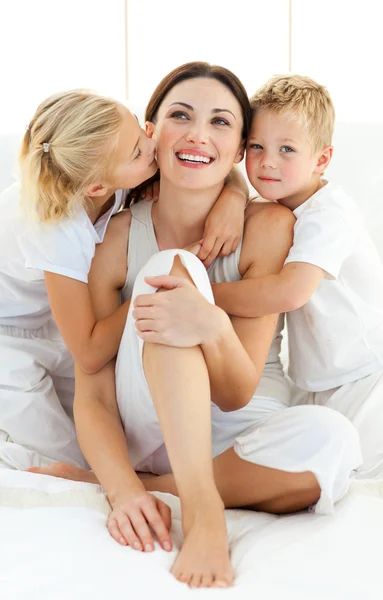 stock image Lively siblings hugging their mother sitting on a bed