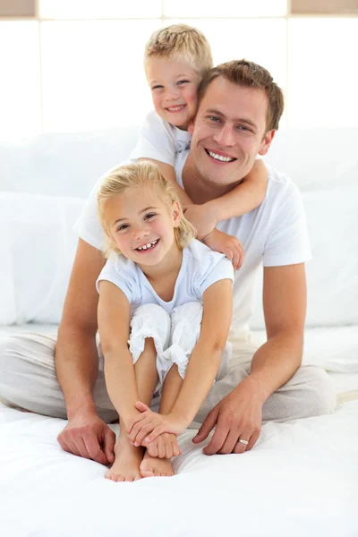 Cute blond boy hugging his dad sitting on a bed — Stock Photo, Image