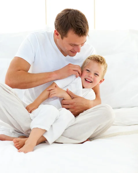 Feliz padre jugando con su hijo en una cama — Foto de Stock