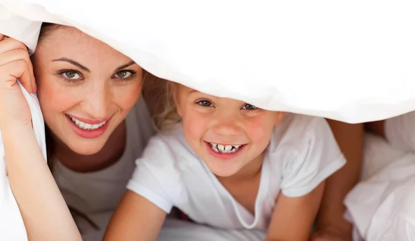 Glückliche Mutter und ihr blondes Mädchen spielen zusammen auf einem Bett — Stockfoto
