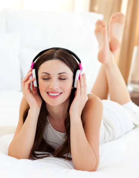 Donna attraente sdraiata sul letto ad ascoltare musica — Foto Stock
