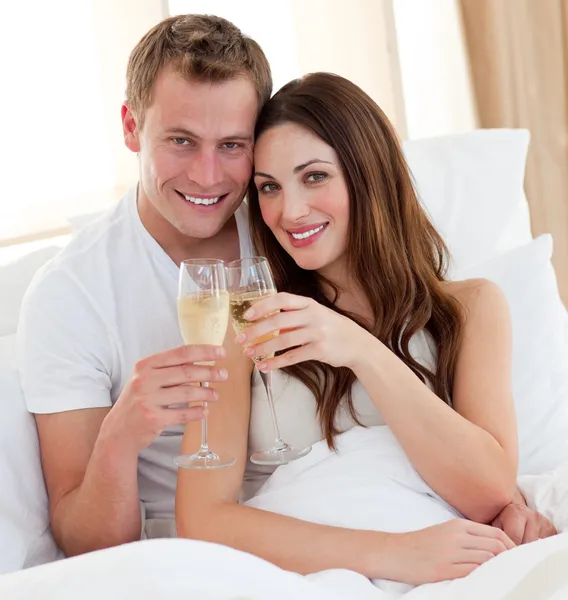 Amante casal bebendo champanhe deitado na cama — Fotografia de Stock