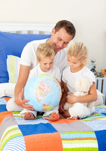 Blond broers en zussen en hun vader kijken naar een terrestrische globe — Stockfoto