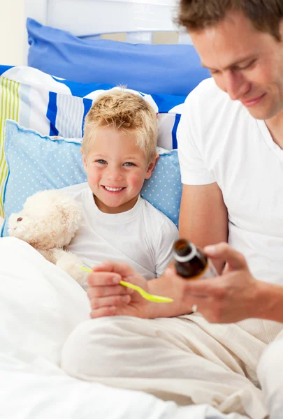 Ayah tersenyum memberikan sirup obat batuk untuk anaknya yang sakit — Stok Foto