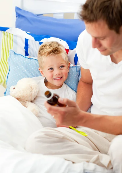 Knappe vader hoestsiroop geven aan zijn zieke zoon — Stockfoto