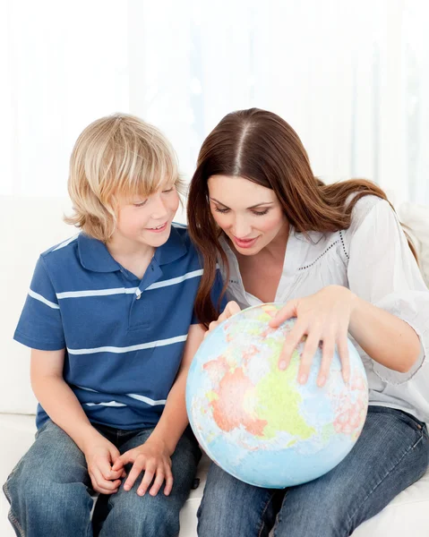 Interested child looking at a terrestrial globe with his mother — Stock Photo, Image