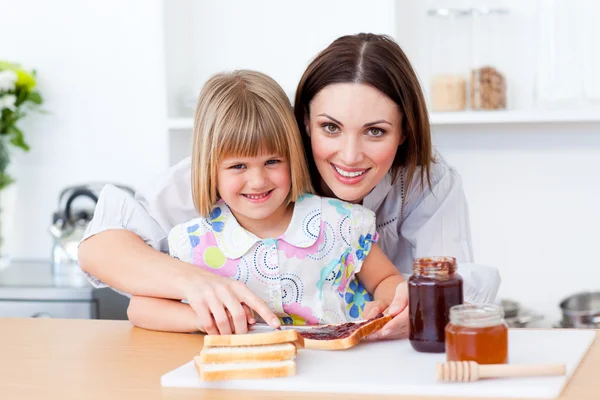Mãe atenta ajudando sua filha a preparar o café da manhã — Fotografia de Stock