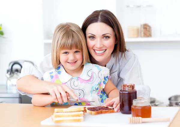 Blond meisje en haar moeder voorbereiding toast — Stockfoto