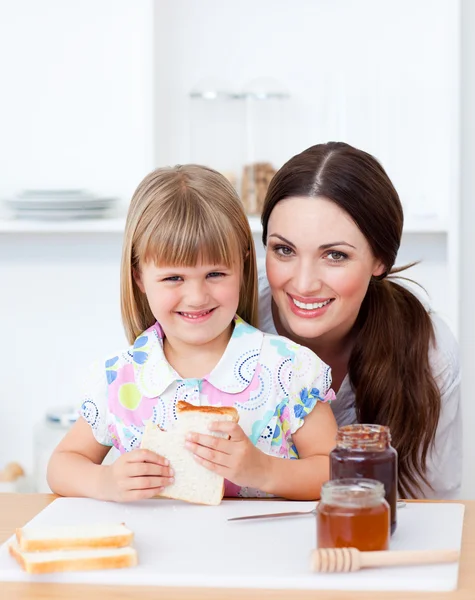 Menina bonito e sua mãe comendo fatias de pão — Fotografia de Stock