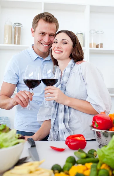 Улыбающаяся пара пьет вино во время приготовления пищи — стоковое фото