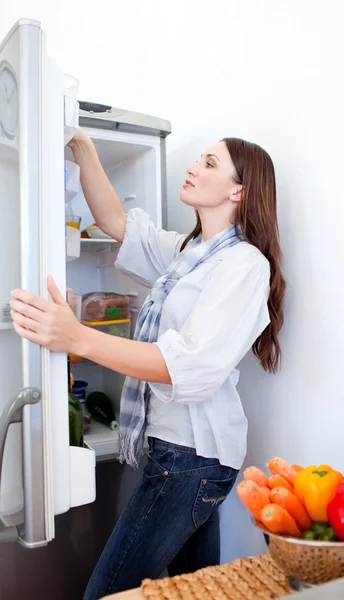 Junge Frau auf der Suche nach etwas im Kühlschrank — Stockfoto
