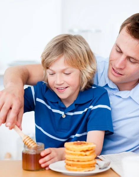 Menino adorável e seu pai colocando mel em waffles — Fotografia de Stock