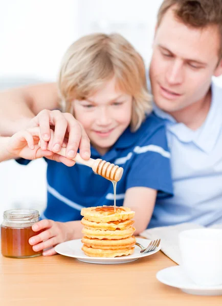Menino adorável e seu pai colocando mel em waffles — Fotografia de Stock