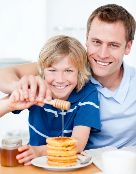 Niño feliz y su padre poniendo miel en los gofres — Foto de Stock