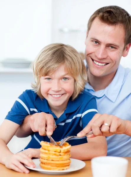 Sorrindo pai e seu filho comendo waffles — Fotografia de Stock