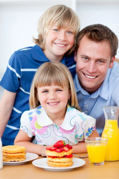 Família feliz comendo waffles com morangos — Fotografia de Stock