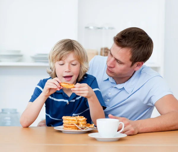 Encantador padre y su hijo comiendo gofres — Foto de Stock