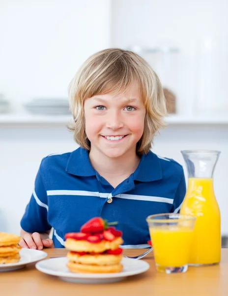 Smiling boy eating waffles with strawberries — Stock Photo, Image