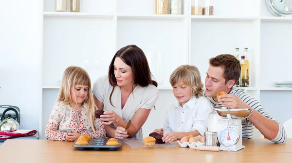 Alegre familia comiendo magdalenas en la cocina — Foto de Stock