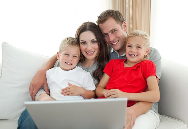Веселая семья за компьютером сидит на диване — стоковое фото