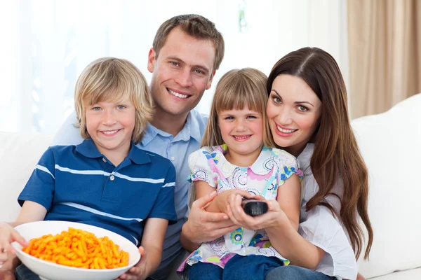 Famille heureuse regarder la télévision et manger des chips — Photo