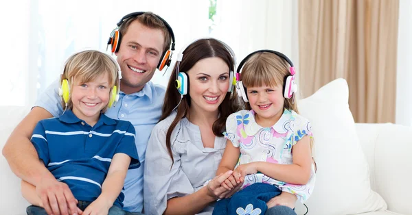Smiling family listening music with headphones — Stock Photo, Image