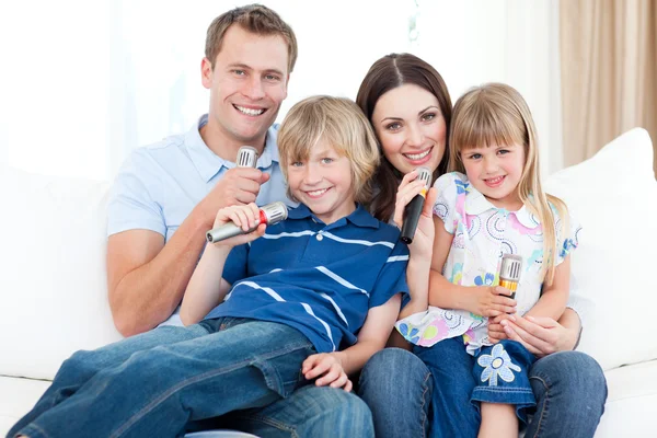 Smiling young family singing a karaoke together — Stock Photo, Image