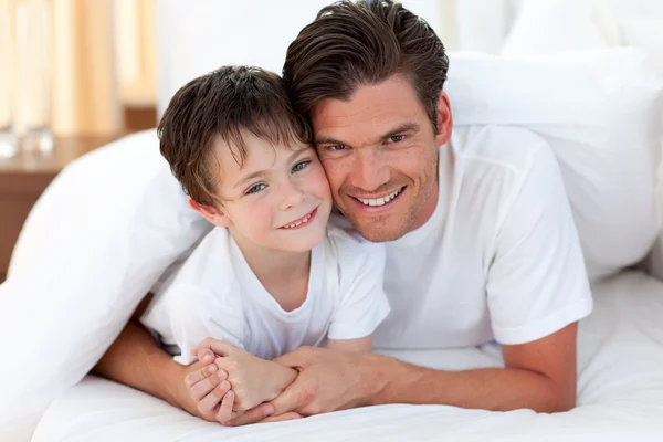 微笑的父亲和他的儿子躺在床上 — 图库照片