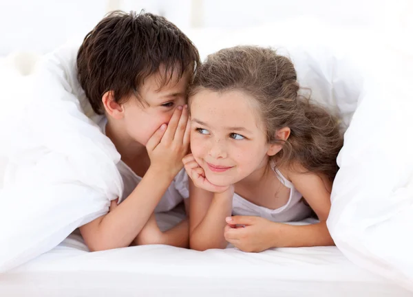 Братья и сёстры играют на кровати родителей — стоковое фото