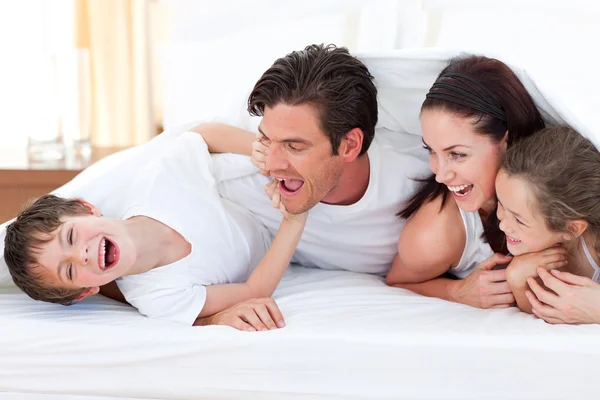 Familia feliz divirtiéndose acostado en la cama —  Fotos de Stock