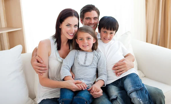 Портрет улыбающейся семьи сидящей на диване — стоковое фото