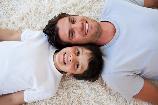 Glimlachend vader en zijn zoon op de vloer liggen — Stockfoto